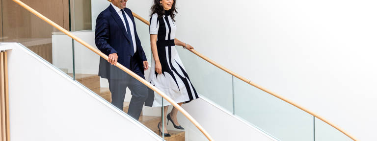 Male and Female Lazard Colleagues Walk Down Set of Stairs