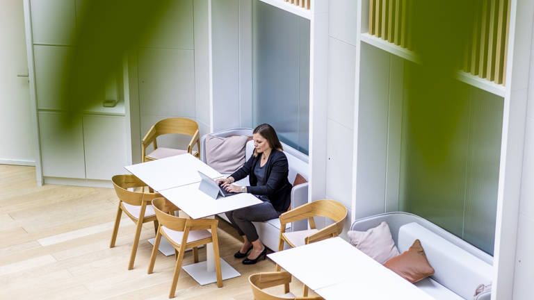 Woman sitting at the Lazard cafeteria working on her computer
