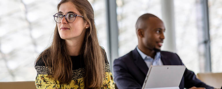 A woman thinking with a man in the background